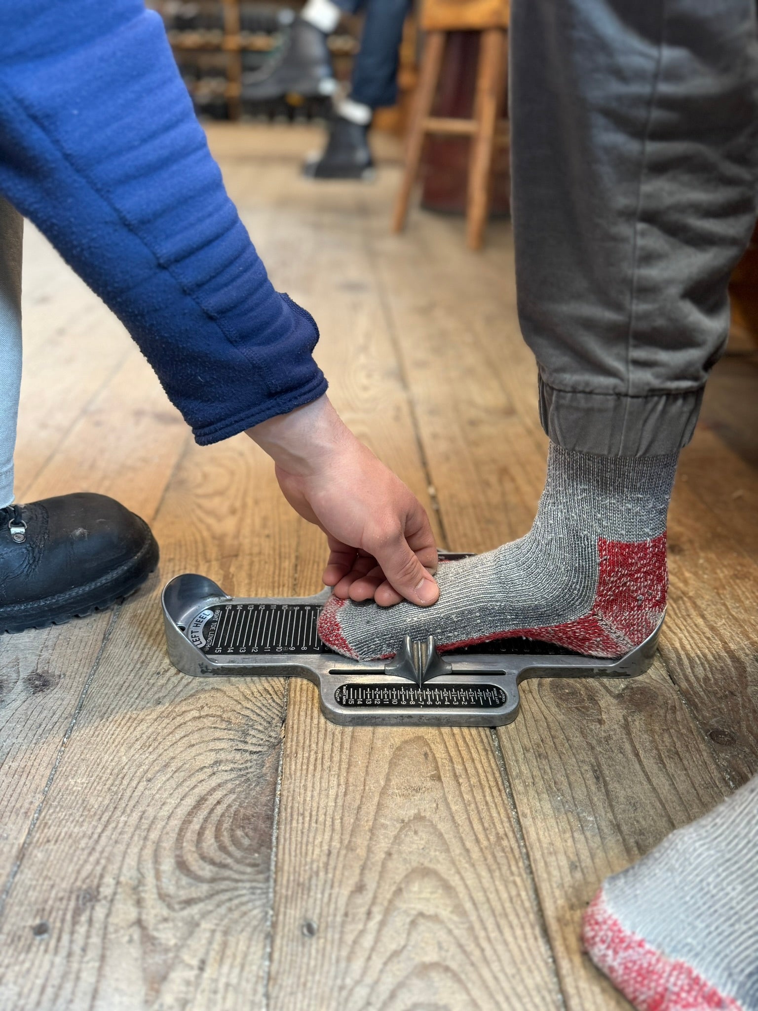 Limmer employee sizing a customer's foot with footwear industry standard brannock device