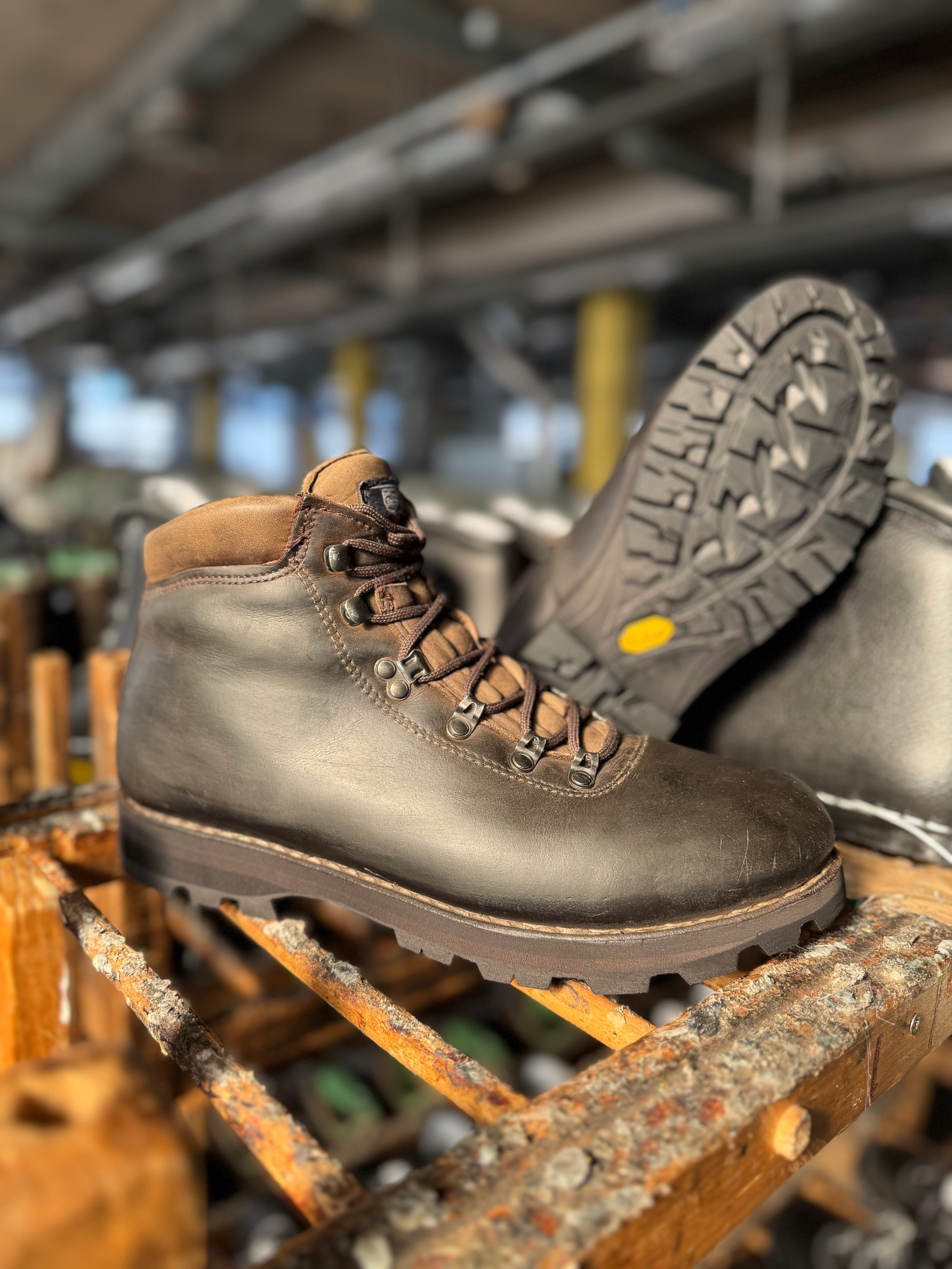 Brown leather boot with a rugged sole on a wooden surface