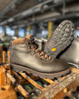 Brown leather boot with a rugged sole on a wooden surface