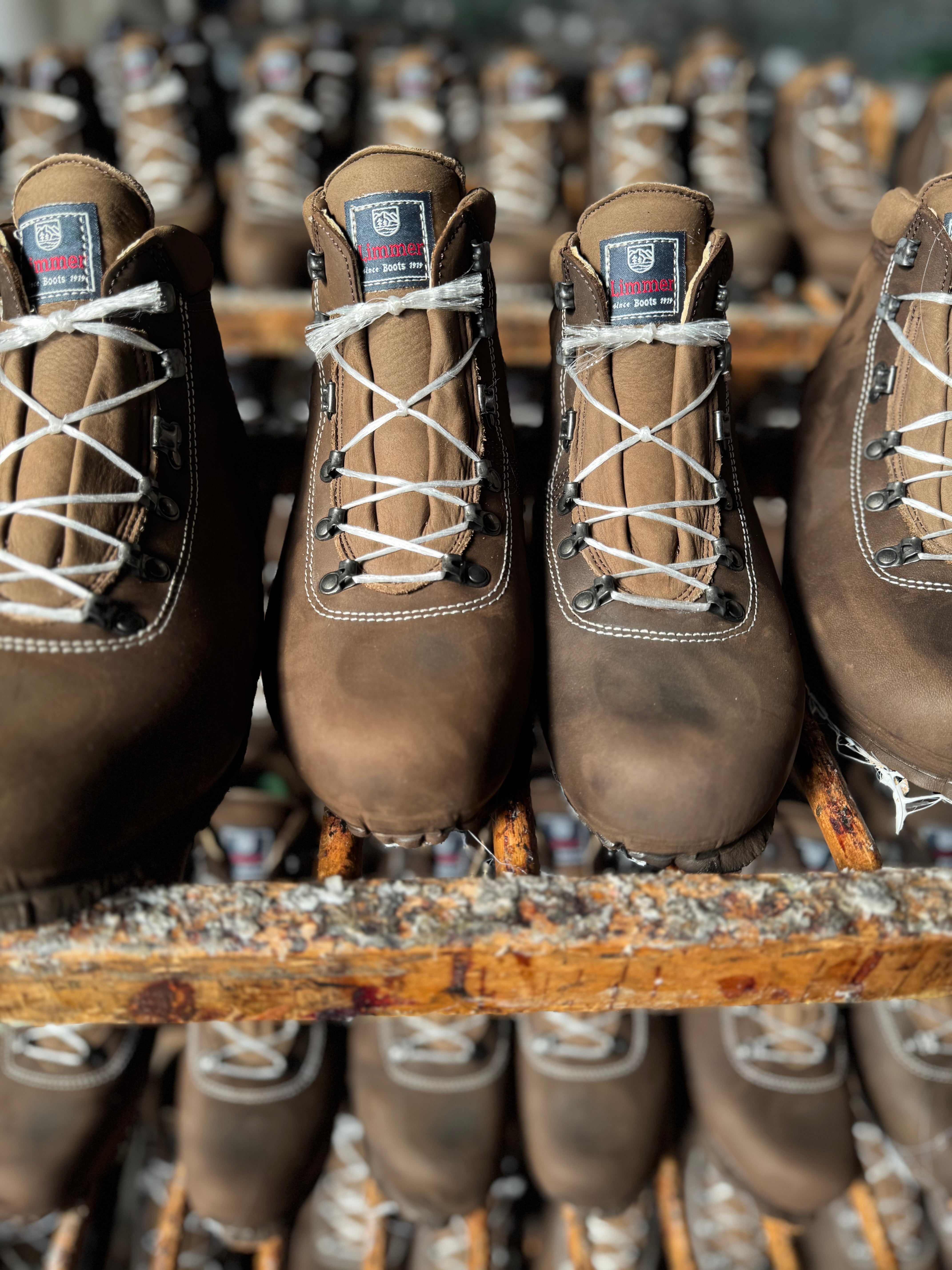 Brown work boots with white laces on a wooden shelf.