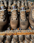 Brown work boots with white laces on a wooden shelf.