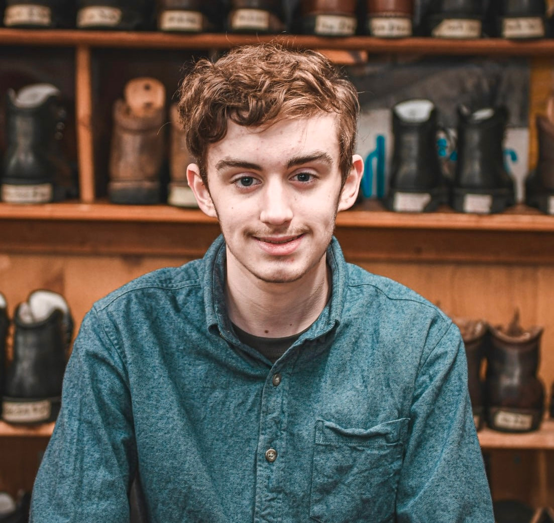 Person wearing a teal shirt in a shoe store with shelves of shoes in the background